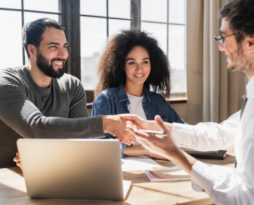 couple talking to loan officer with laptop on desk