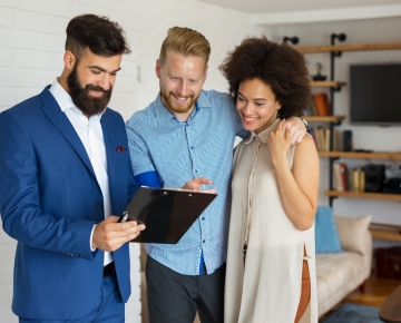 man in blue suit showing tablet content to couple in home