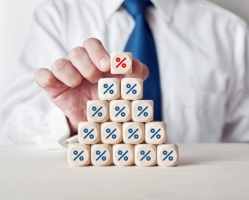 man wearing tie sitting behind blocks with percentage signs on them