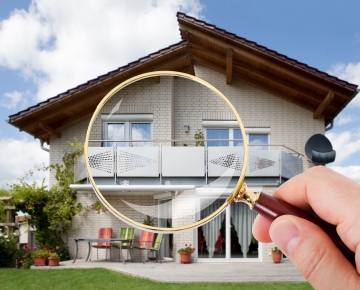 hand holding magnifying glass over home