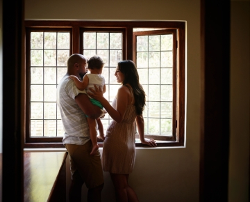 Couple looking out window with child